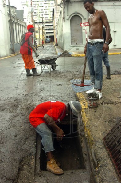 Norman Grindley /Deputy Chief Photographer 
Workmen from KSAC clear blocked drains along Harbour Street in Kingston yesterday.
